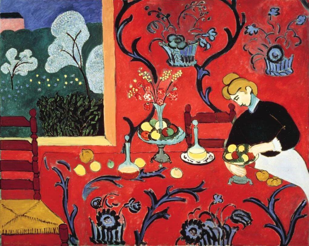 A woman setting a table for dessert in a red room with blue arabesques