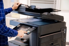 Person standing at printer pressing button